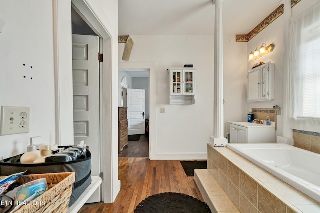 bathroom with vanity, hardwood / wood-style floors, and tiled bath