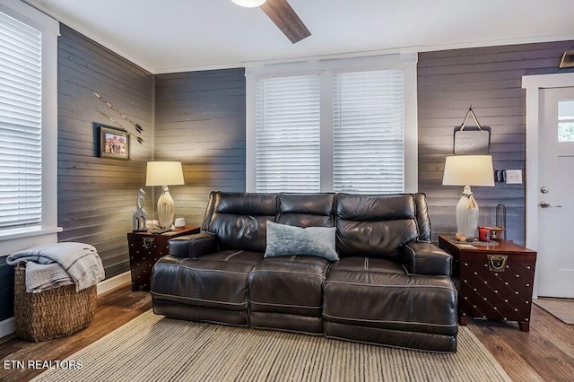 living room with wood walls, hardwood / wood-style floors, and ceiling fan