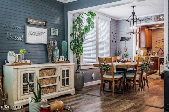 dining area with ornamental molding, a chandelier, dark hardwood / wood-style floors, and wood walls