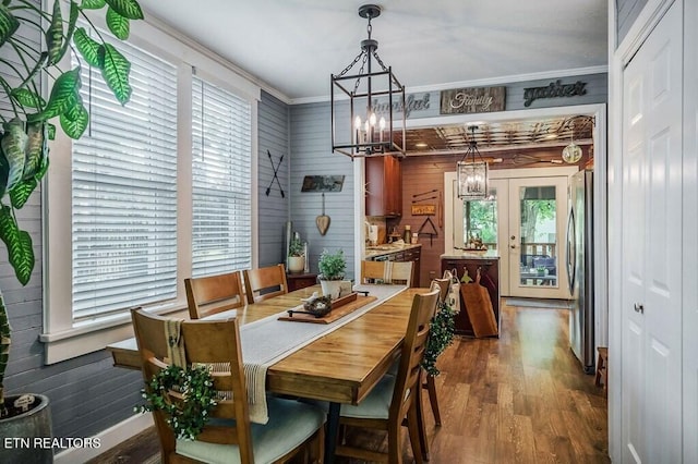 dining area featuring wooden walls, crown molding, wood-type flooring, and plenty of natural light