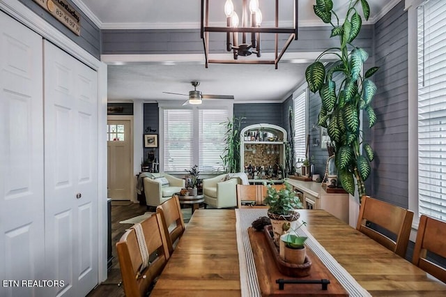 dining space featuring crown molding, hardwood / wood-style floors, ceiling fan with notable chandelier, and plenty of natural light