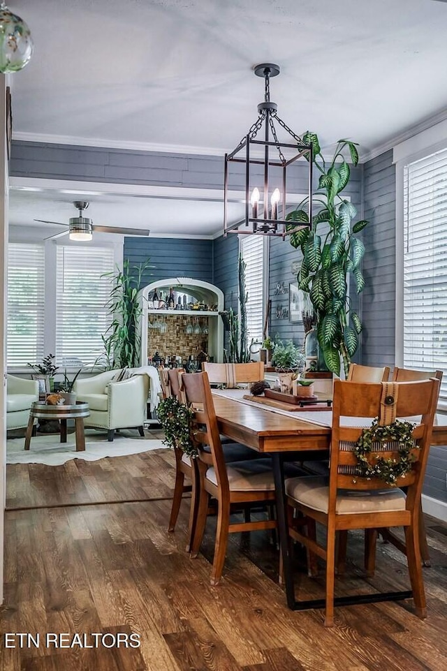 dining room featuring ornamental molding, a notable chandelier, hardwood / wood-style flooring, and wood walls