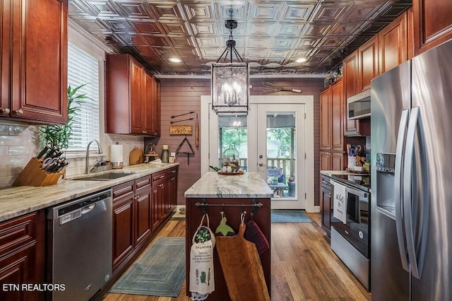 kitchen with stainless steel appliances, sink, a center island, decorative light fixtures, and dark hardwood / wood-style flooring