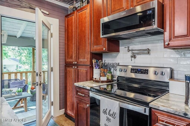 kitchen with light hardwood / wood-style floors, light stone countertops, stainless steel appliances, and backsplash