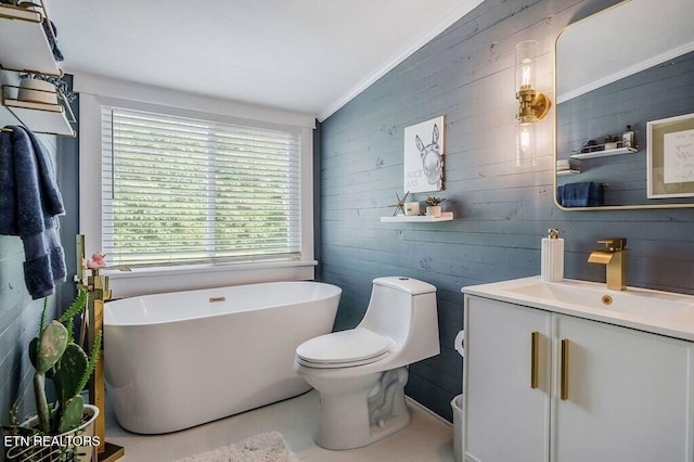 bathroom featuring lofted ceiling, toilet, ornamental molding, vanity, and a tub to relax in