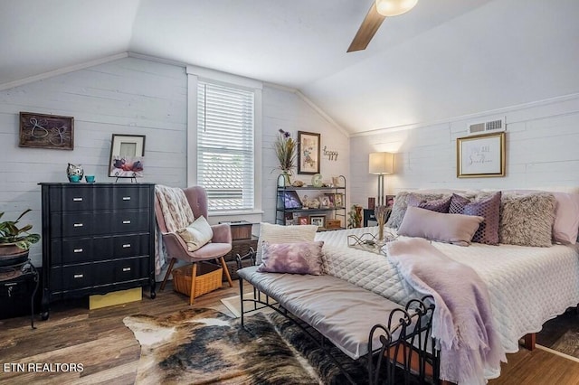 bedroom with ceiling fan, wooden walls, vaulted ceiling, and dark hardwood / wood-style flooring