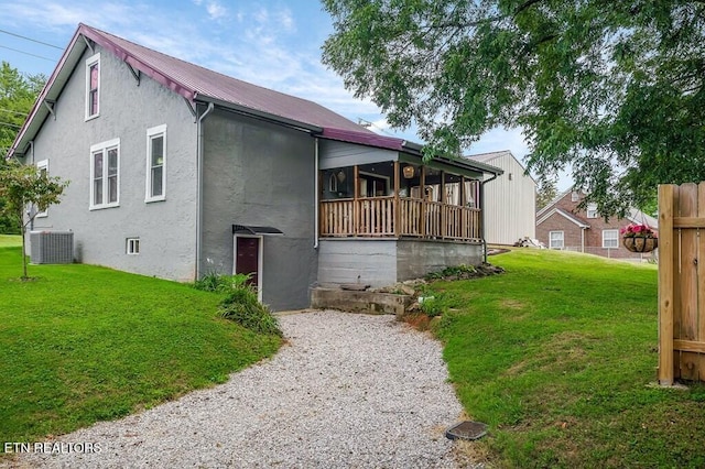 view of front of property featuring a sunroom, a front yard, and central AC