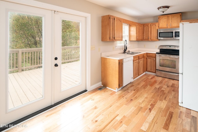 kitchen featuring stainless steel appliances, sink, and light hardwood / wood-style flooring