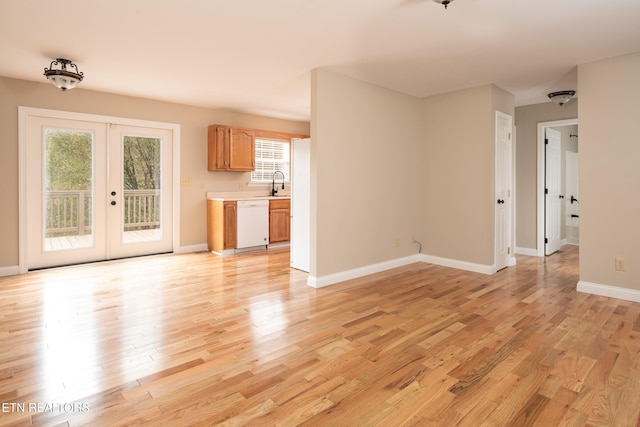 unfurnished living room with sink, french doors, and light hardwood / wood-style flooring