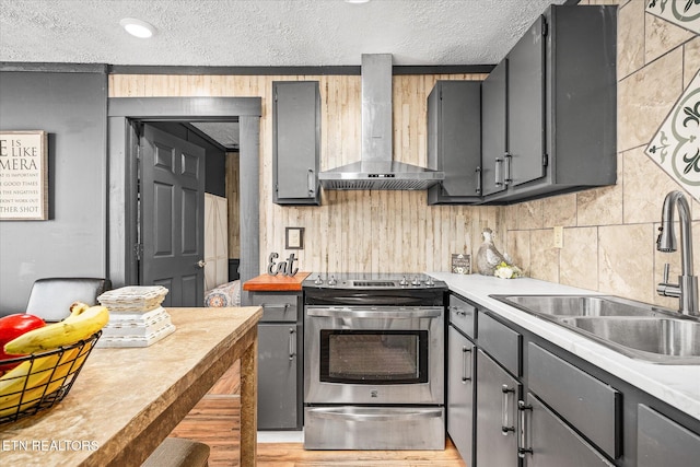 kitchen featuring wall chimney exhaust hood, sink, stainless steel range with electric cooktop, and gray cabinets