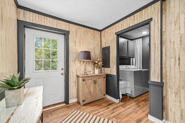 entryway featuring electric panel, independent washer and dryer, light wood-type flooring, and wood walls