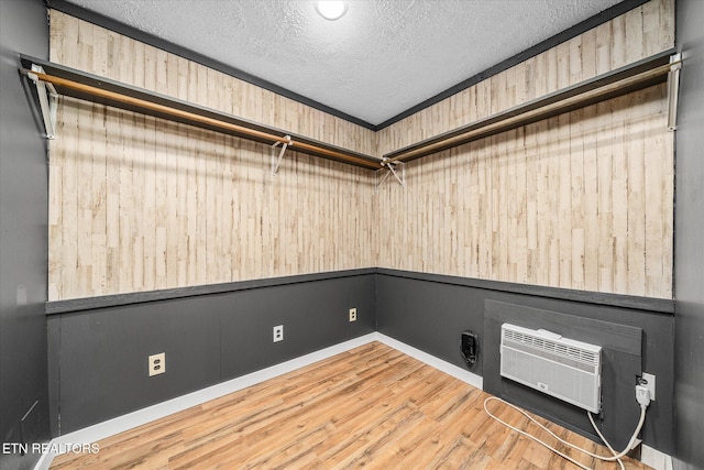 washroom featuring a wall unit AC, wood walls, a textured ceiling, and hardwood / wood-style flooring