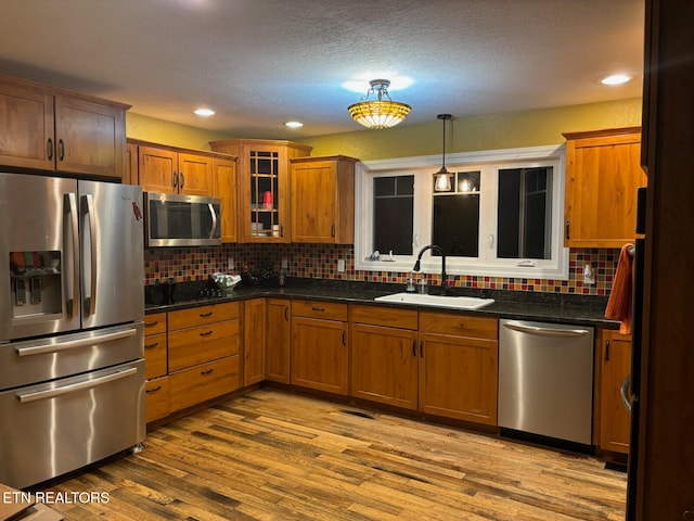 kitchen with backsplash, light wood-type flooring, sink, and appliances with stainless steel finishes