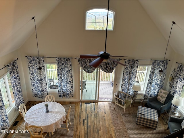 dining area featuring hardwood / wood-style flooring, high vaulted ceiling, and plenty of natural light