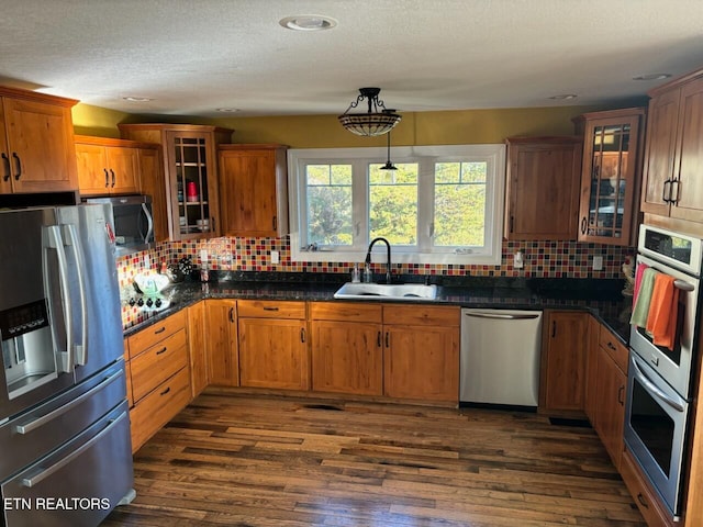 kitchen featuring sink, hanging light fixtures, stainless steel appliances, tasteful backsplash, and dark hardwood / wood-style floors