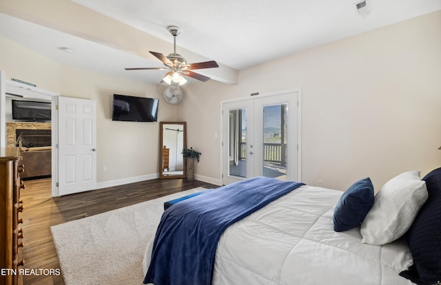 bedroom with ceiling fan, a fireplace, dark wood-type flooring, french doors, and access to outside