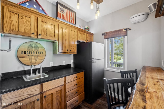 kitchen with stainless steel refrigerator, sink, wooden counters, dark hardwood / wood-style floors, and hanging light fixtures