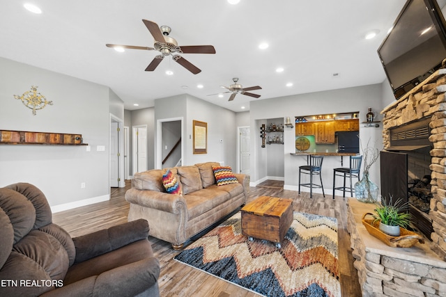 living room with hardwood / wood-style floors, a fireplace, and ceiling fan