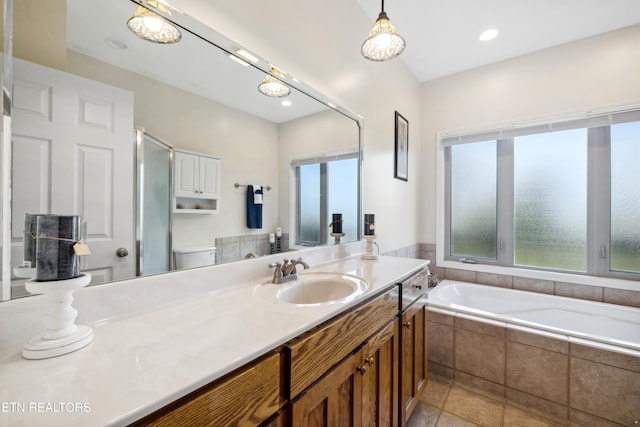 bathroom with toilet, vanity, tile patterned floors, and a relaxing tiled tub