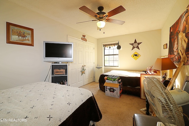 bedroom with ceiling fan, light colored carpet, a textured ceiling, and a closet