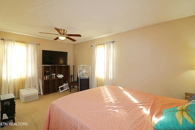 bedroom featuring ceiling fan, multiple windows, a textured ceiling, and carpet