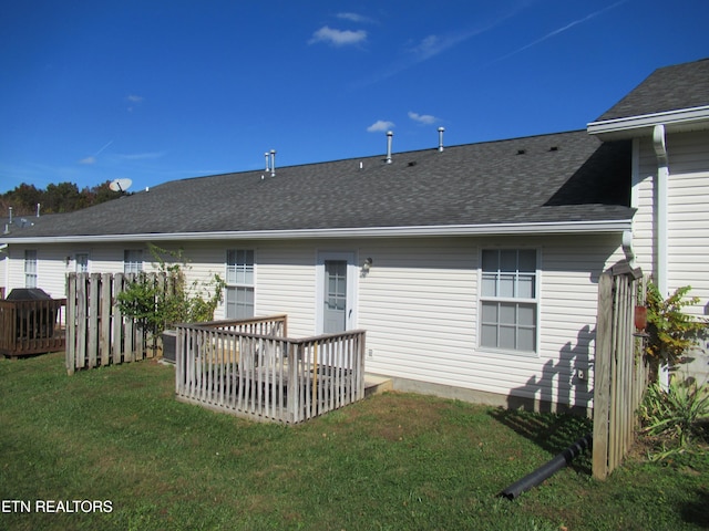 back of property with a wooden deck and a lawn