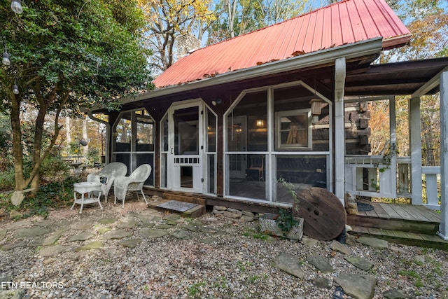 back of property with a wooden deck and a sunroom