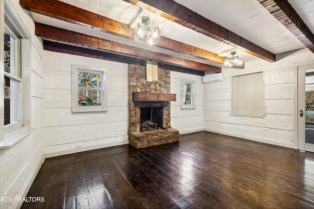 unfurnished living room featuring a wealth of natural light, hardwood / wood-style floors, a wall unit AC, and beam ceiling