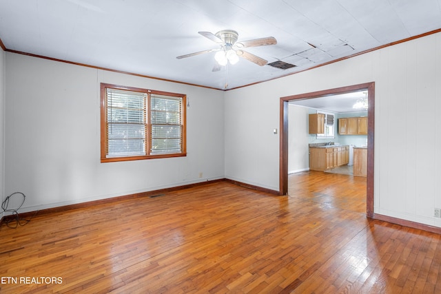 spare room with ceiling fan, light wood-type flooring, and crown molding