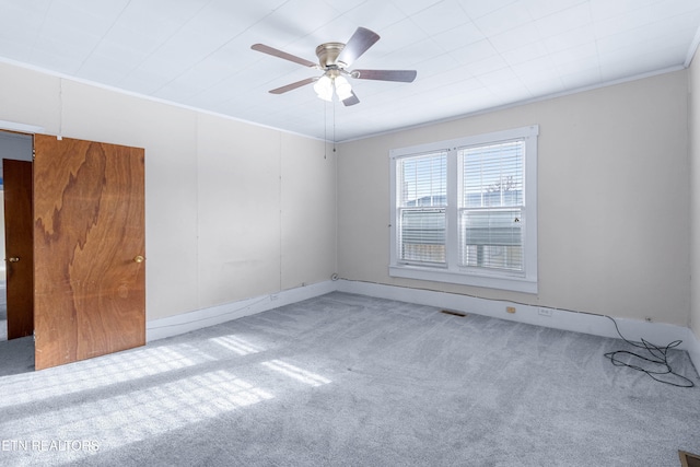 spare room featuring ceiling fan, light colored carpet, and ornamental molding