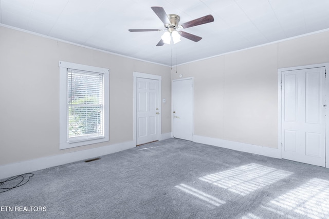 carpeted spare room with ceiling fan and crown molding