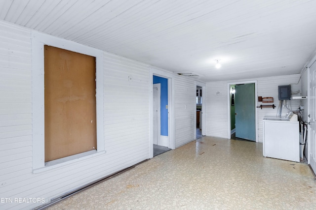 spare room with electric panel, wooden walls, and washer / dryer