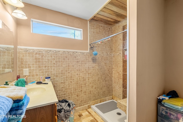 bathroom with tile walls, vanity, and a tile shower