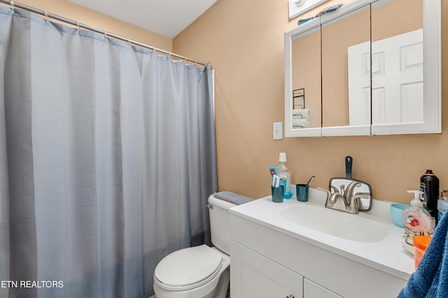 bathroom with curtained shower, vanity, and toilet