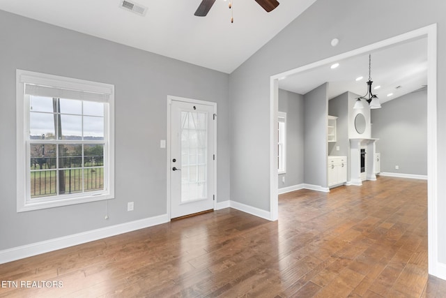 unfurnished living room featuring wood finished floors, lofted ceiling, ceiling fan, and visible vents
