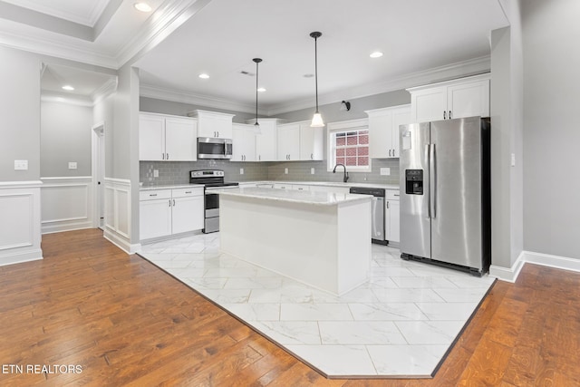 kitchen with stainless steel appliances, white cabinetry, hanging light fixtures, and a center island