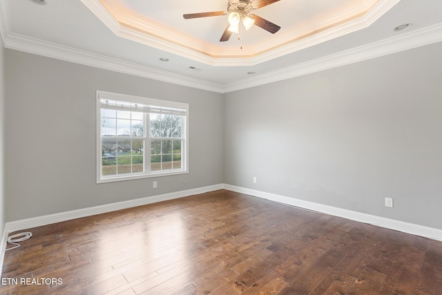 spare room with baseboards, ceiling fan, a raised ceiling, and dark wood finished floors