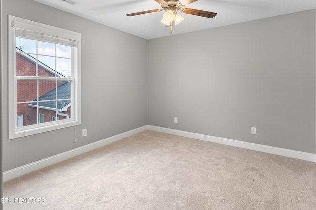 empty room featuring baseboards, a ceiling fan, and light colored carpet