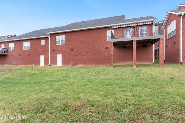 back of property featuring a lawn and brick siding