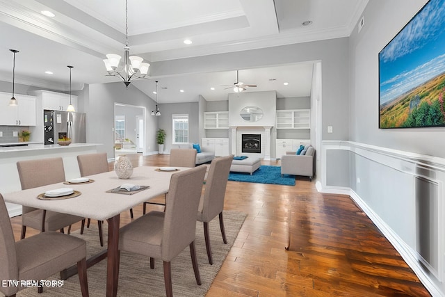 dining space featuring light wood finished floors, a fireplace, ornamental molding, recessed lighting, and ceiling fan with notable chandelier