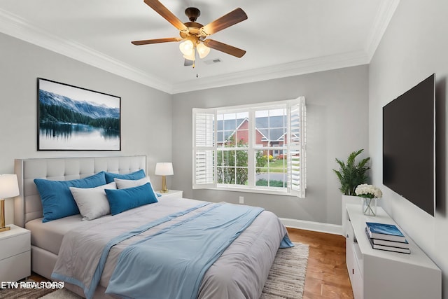 bedroom featuring wood finished floors, baseboards, visible vents, ceiling fan, and ornamental molding