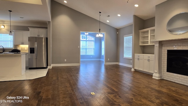 unfurnished living room with a fireplace, dark wood-style flooring, baseboards, recessed lighting, and an inviting chandelier