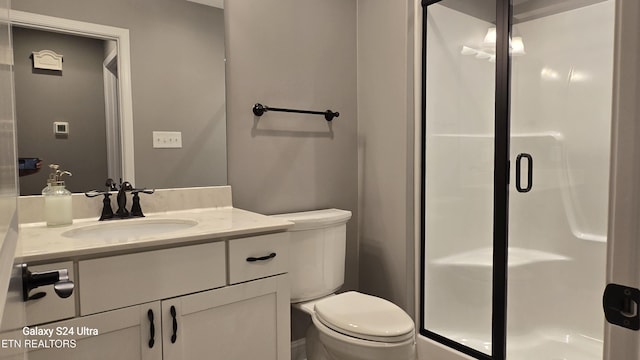 bathroom featuring toilet, vanity, and a stall shower