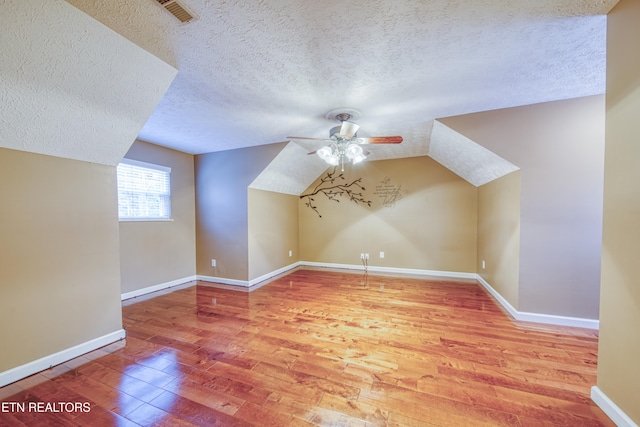 additional living space with wood-type flooring, a textured ceiling, ceiling fan, and lofted ceiling