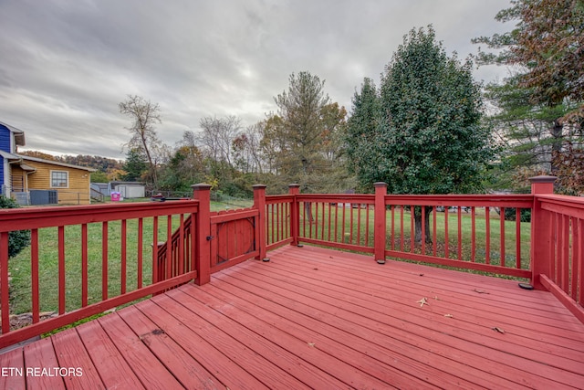 wooden deck with a shed and a lawn