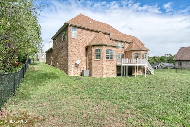 back of house with a deck, stairs, brick siding, a fenced backyard, and a lawn