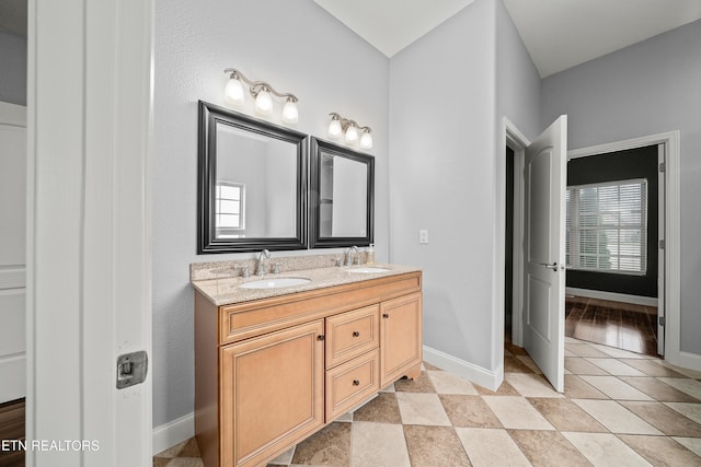 full bath featuring baseboards, double vanity, and a sink