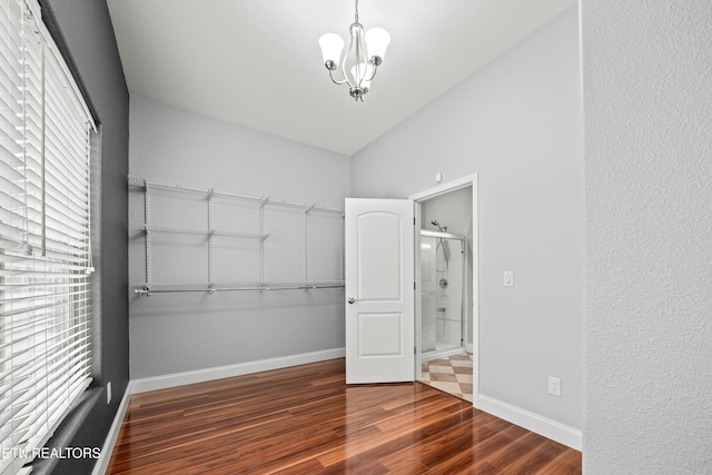 spacious closet featuring dark hardwood / wood-style floors, a chandelier, and lofted ceiling