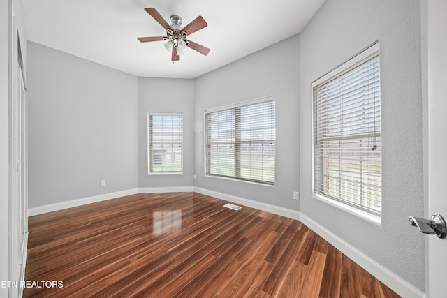 empty room with ceiling fan, baseboards, dark wood-style floors, and visible vents