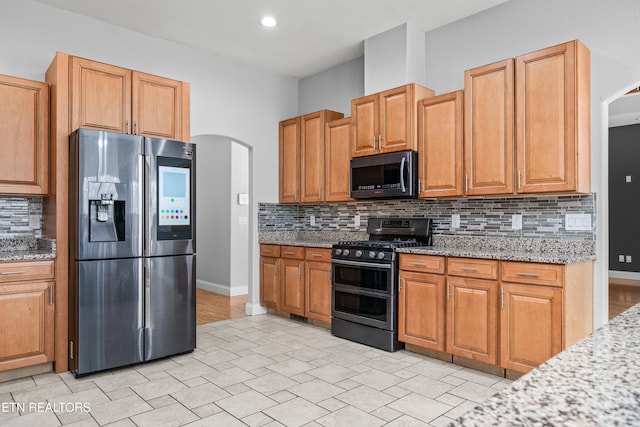 kitchen featuring appliances with stainless steel finishes, light stone counters, and backsplash